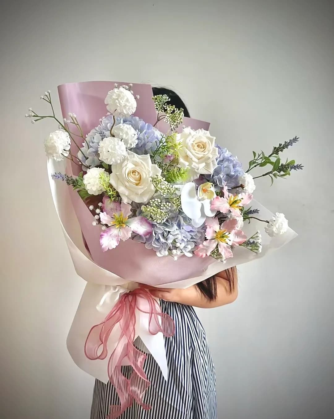 Bó hoa vải cầm tay gồm cẩm tú cầu xanh tím, hồng kem, lan hồ điệp trắng và oải hương, gói giấy tím buộc ruy băng hồng – Flowerly Đà Nẵng